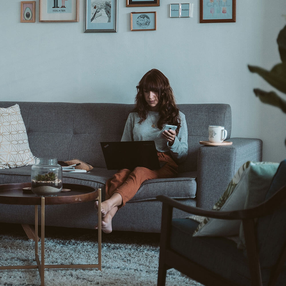 Une personne sur un canapé avec son mobile dans la main