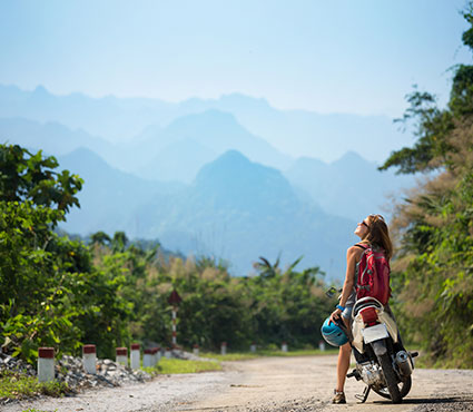 Jeune femme assis en amazone sur une moto sur une route de campagne