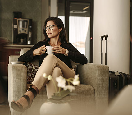 Une dame buvant un café dans un espace lounge assise dans un fauteuil confortable
