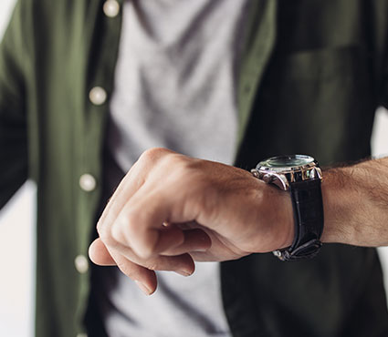 Une montre sur le poignet d'un homme qui regarde l'heure